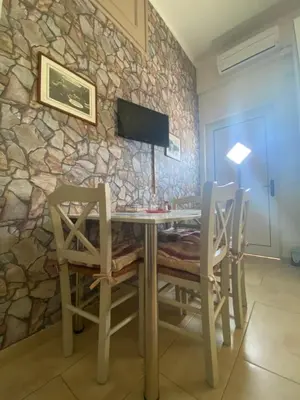 a dining room with a table and chairs against a stone wall at Maria & Zachos House in Kissamos