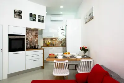 a kitchen with white cabinets and a table and chairs at Elmaya's Duplex in Kissamos