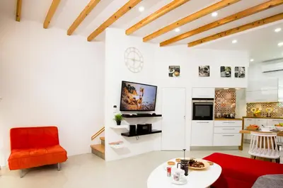 a living room with a red chair and a table at Elmaya's Duplex in Kissamos