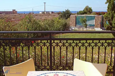 a balcony with a table and chairs on a fence at Monachus Monachus in Frangokastello