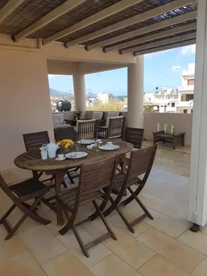 a wooden table and chairs on a patio at Rastoni Apartments in Kissamos