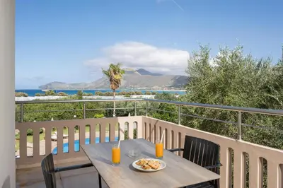 a table on a balcony with a view of the ocean at Petritos Rooms and Studios in Falasarna