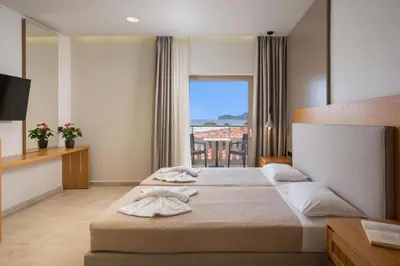 a hotel room with two beds and a large window at Petritos Rooms and Studios in Falasarna