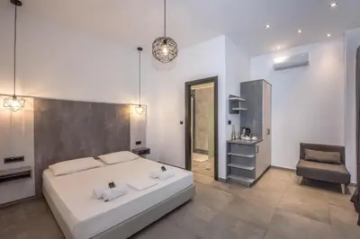 a white bedroom with a bed and a chair at Xasteria in Elafonisi