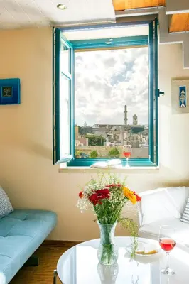 a living room with a window and a table with flowers at Boutique Hotel Fortino in Chania Town