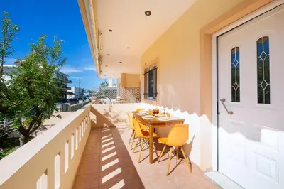 a patio with a table and chairs on a balcony at Aptera Beach Apartment in Kato Daratso