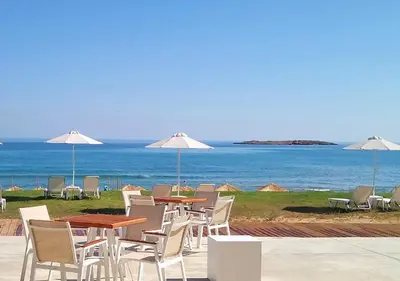 a group of tables with chairs and umbrellas on the beach at Aptera Beach Apartment in Kato Daratso