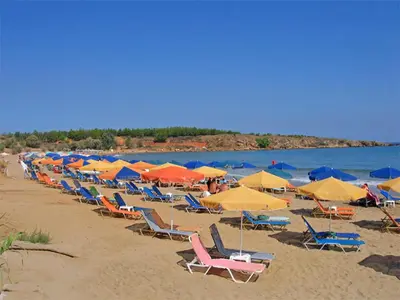 a bunch of chairs and umbrellas on a beach at Aptera Beach Apartment in Kato Daratso