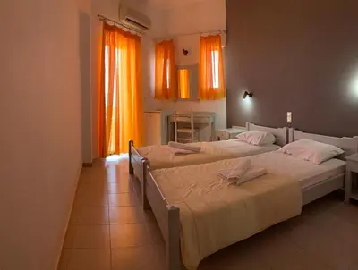 two beds in a room with orange curtains at Kalami Rooms in Falasarna