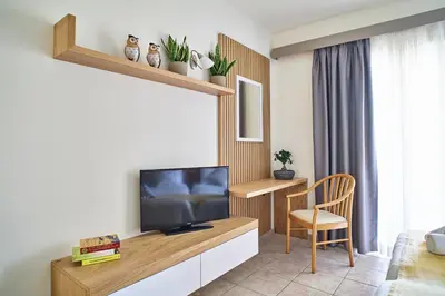 a living room with a television and a chair at Pegasus Hotel in Stalos