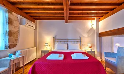 a bedroom with a red bed and two blue chairs at Kores Boutique Houses in Chania Town