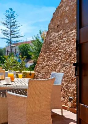 a table and chairs on a patio with a brick wall at Kores Boutique Houses in Chania Town
