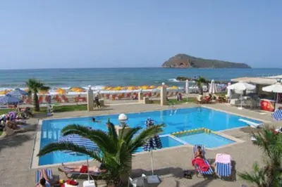 a large swimming pool next to a beach with the ocean at Marina Sands in Agia Marina Nea Kydonias