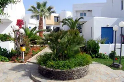 a garden with palm trees and plants in front of a building at Marina Sands in Agia Marina Nea Kydonias
