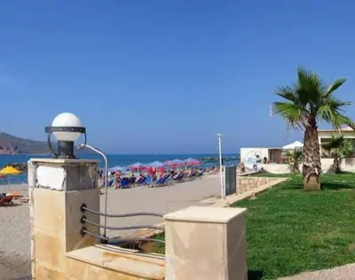 a view of a beach with a palm tree and the ocean at Marina Sands in Agia Marina Nea Kydonias