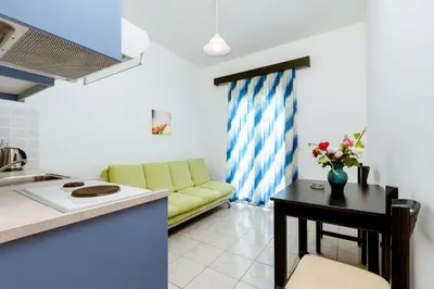 a kitchen and a living room with a yellow couch at Asterina Seaside Apartments in Kalyves