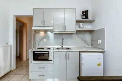 a kitchen with white cabinets and a sink at Asterina Seaside Apartments in Kalyves