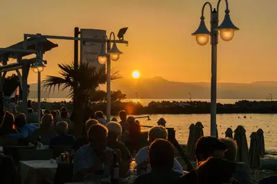 a group of people sitting at tables watching the sunset at Marika Beach Hotel in Plataniás