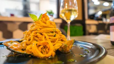 a plate of pasta on a table with a glass of wine at Marika Beach Hotel in Plataniás