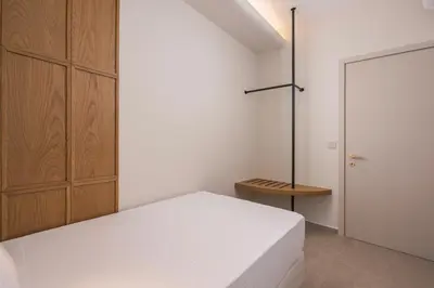 a bedroom with a white bed and a wooden cabinet at Marika Beach Hotel in Plataniás