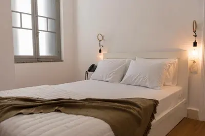 a bedroom with a bed with white sheets and a window at Kumba in Chania Town