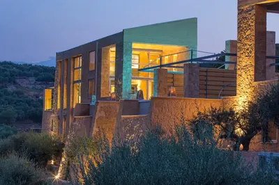 a building with lights on in front of it at Olea Villas - Infinity Pool, Hot Tub, Sea Views in Marathi