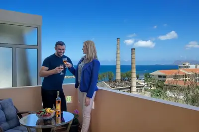 a man and a woman standing on a balcony with wine glasses at Fougaro Apartments in Chania Town