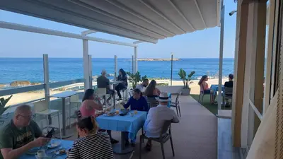 a group of people sitting at tables on the beach at Klinakis Beach Hotel in Chania Town