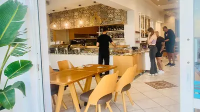 a group of people standing at a counter in a restaurant at Klinakis Beach Hotel in Chania Town