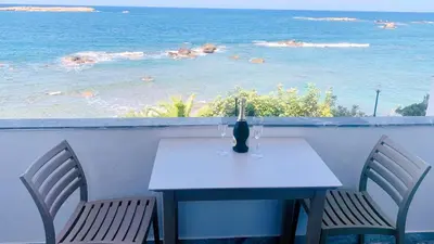 a white table and chairs with a view of the ocean at Klinakis Beach Hotel in Chania Town