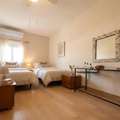 a bedroom with two beds and a table and a mirror at Marianna Apartments in Almirida