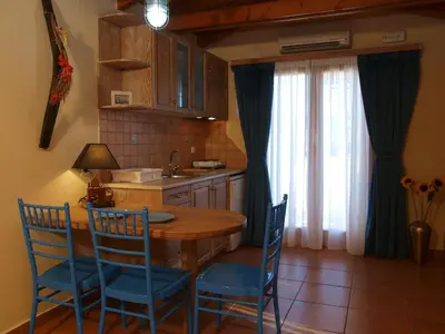 a kitchen with a wooden table and blue chairs at Mylos Hotel Apartments in Plataniás