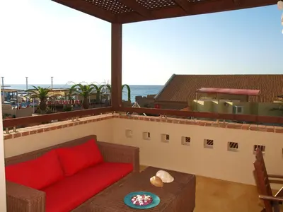 a living room with a red couch on a balcony at Mylos Hotel Apartments in Plataniás