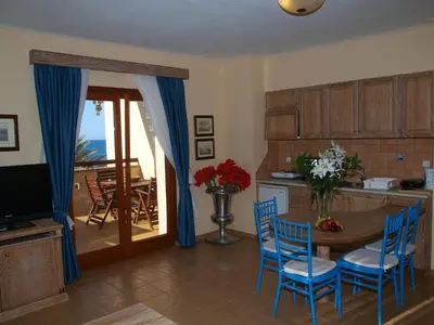 a living room with a table and chairs and a kitchen at Mylos Hotel Apartments in Plataniás