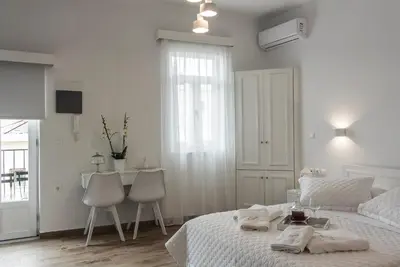 a white bedroom with a bed and a table and chairs at Agapi Suites in Chania Town