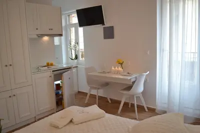 a white kitchen with a table and chairs in a room at Agapi Suites in Chania Town