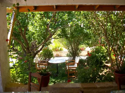 a patio with chairs and a table and trees at Golden Sun Apartments in Falasarna