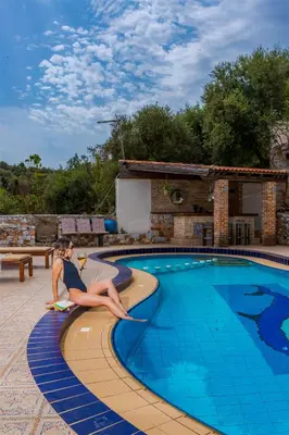 a woman sitting on the edge of a swimming pool at Zen Serenity Retreat with Great Outdoors, Pool & Parking in Áptera