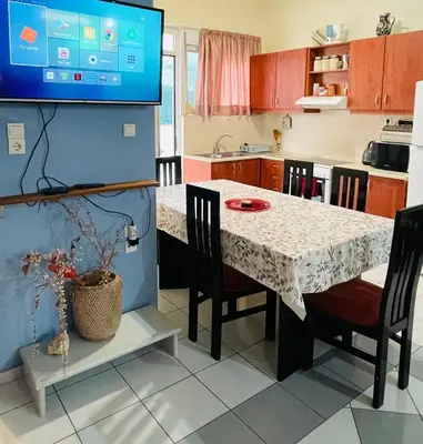 a kitchen with a table with chairs and a tv at Nea Chora cozy apartment close to the beach in Chania Town