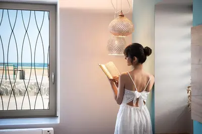 a woman reading a book in front of a window at Ciel Collection Suites in Chania Town