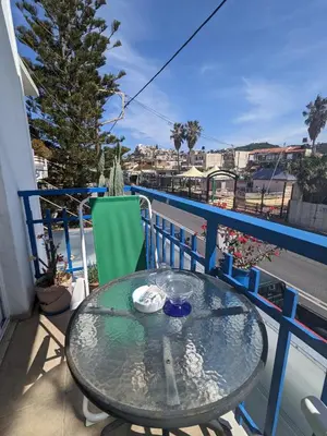 a glass table on a balcony with a view of a street at 2-Bedroom Blue & White House with Garden and Beach in Plataniás