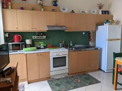 a kitchen with wooden cabinets and a white refrigerator at 2-Bedroom Blue & White House with Garden and Beach in Plataniás