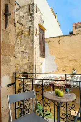 a table with two glasses of wine and fruit on a balcony at Vereniki Suites Chania in Chania Town