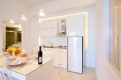 a white kitchen with a bottle of wine on a counter at Gina's home in Kolymvari