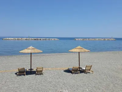 two chairs and two umbrellas on a beach at Gina's home in Kolymvari