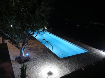 a swimming pool at night with a tree and lights at PALACE Mountain view in Megála Khoráfia