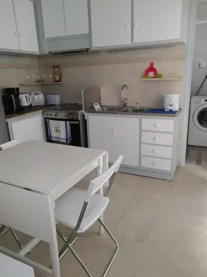 a kitchen with a white table and white cabinets at Zamboli in Chania Town
