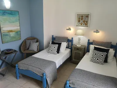 a room with two beds and a chair and a table at Villa Koumos - Crete Holidays With Pool and Views in Gavalochori