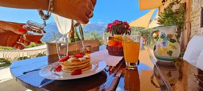 a person eating a plate of pancakes on a table at Thymes traditional house in Loúlos