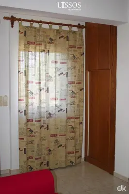 a curtain in a room with a red couch at Chania Lissosaparments in Kato Daratso